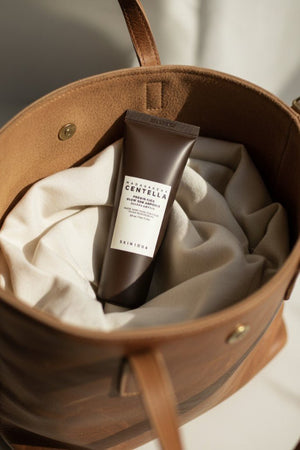 SKIN1004 Madagascar Centella Probio-Cica Glow Sun Ampoule i en brun väska med tygfoder.