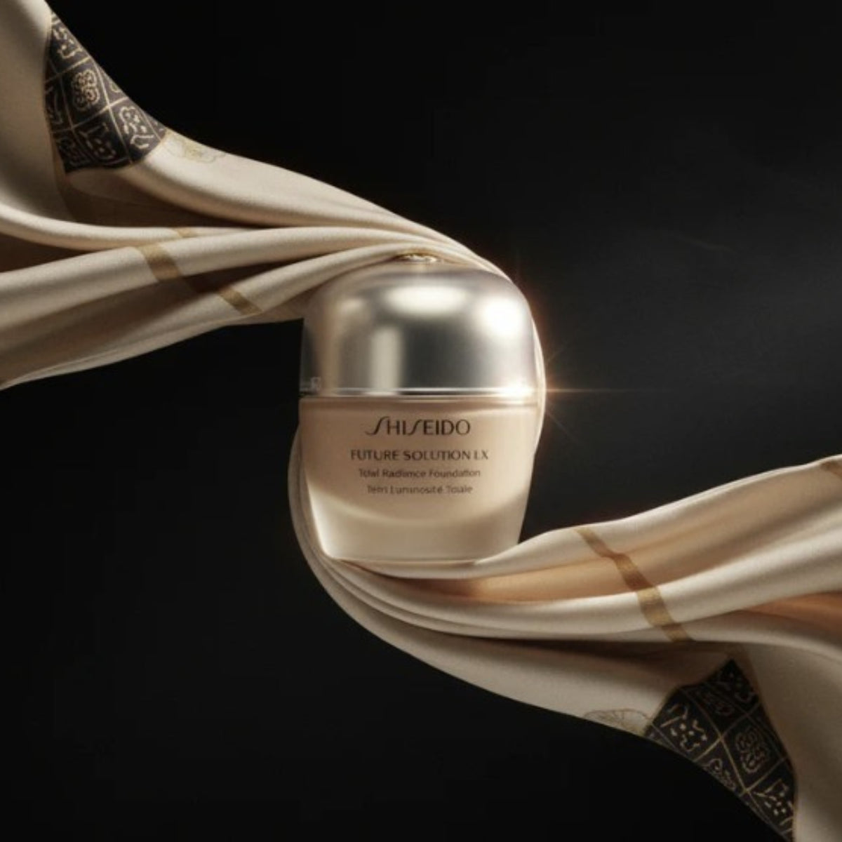 Shiseido foundationburk med silvrigt lock samt beige swatch på tyg