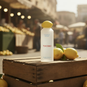 TOCOBO AHA/BHA-lemon tonerflaska med gul kork på trälåda, omgiven av citroner